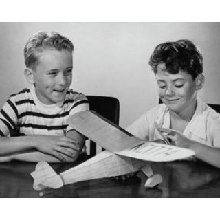 Boy making a model airplane and another boy sitting beside him Poster Print (18 x 24)